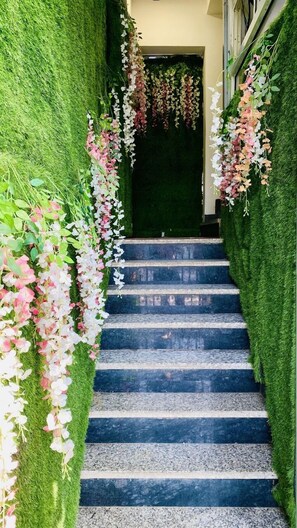 Un escalier dont les murs sont recouverts de gazon synthétique et décoré de guirlandes de fleurs suspendues.