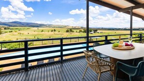 Un espace extérieur abrité, avec une table dressée pour un repas, offrant une vue sur un paysage pittoresque.