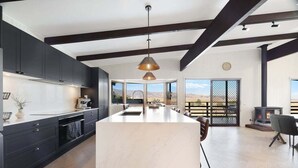 Une cuisine moderne avec des meubles de couleur sombre, un grand îlot central et un luminaire suspendu.