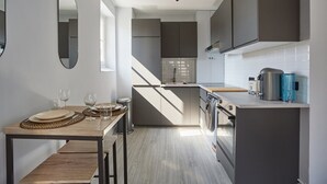 A modern kitchen with grey cabinets, a built-in oven, and a coffee machine. - Sublim Studio Beaubourg/le Marais (Paris)