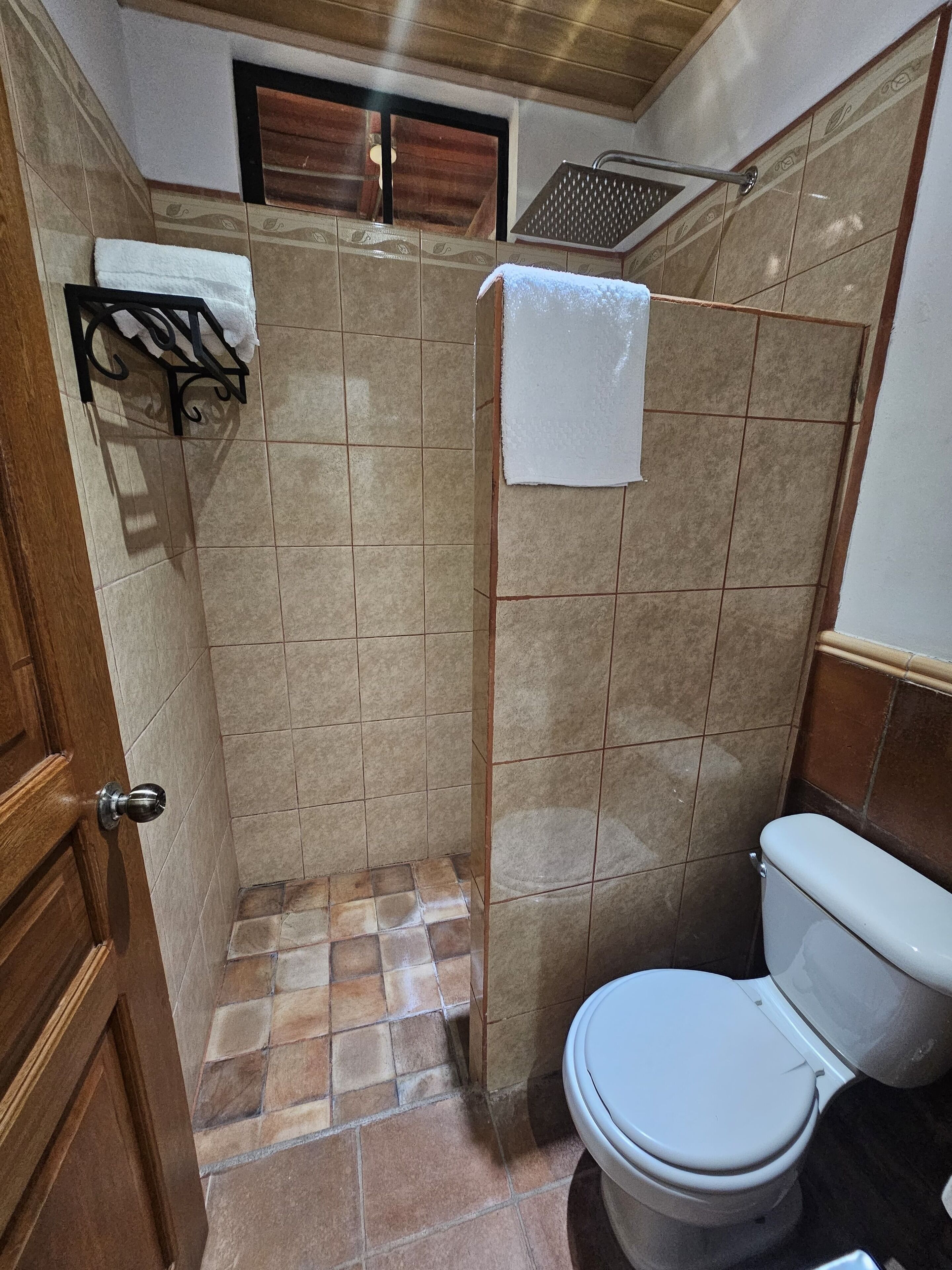 Un baño pequeño con inodoro, ducha y lavamanos.