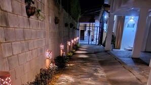A stone-paved pathway with decorative lights along the walls, leading to a building entrance. - Hotel Nica Valley (Rivas)