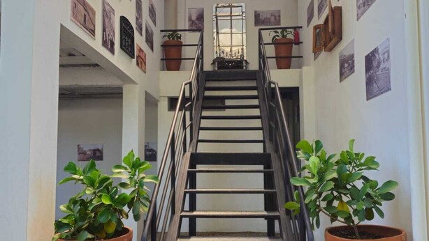 A staircase with terracotta planters on either side, leading to a room with a skylight and framed pictures on the walls. - Hotel Nica Valley (Rivas)
