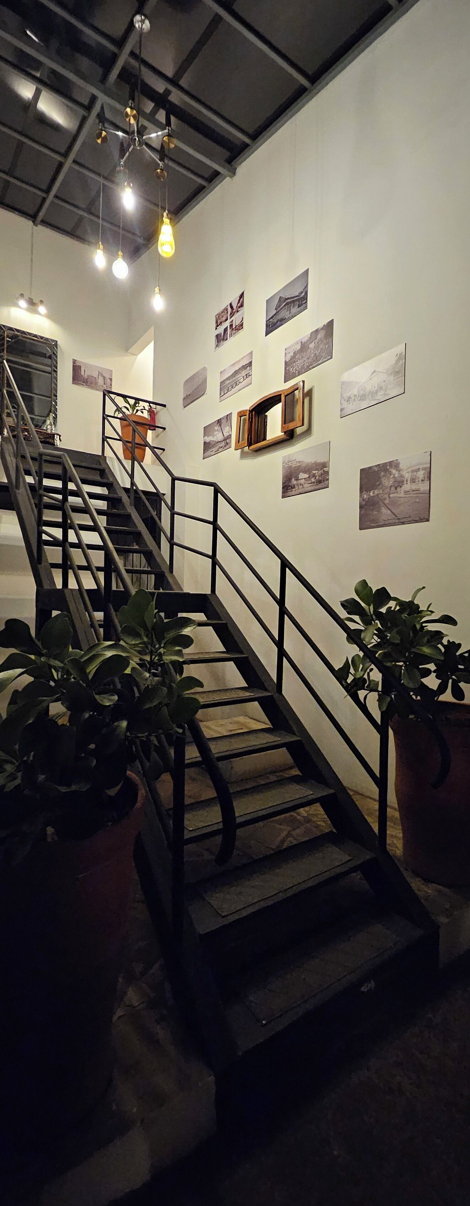 A staircase with metal railings and potted plants, leading to a higher floor.