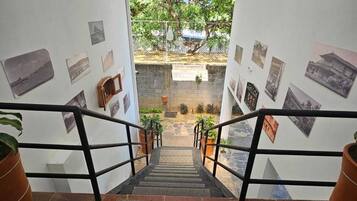 Una escalera conduce a un patio con plantas en macetas y vistas a árboles.
