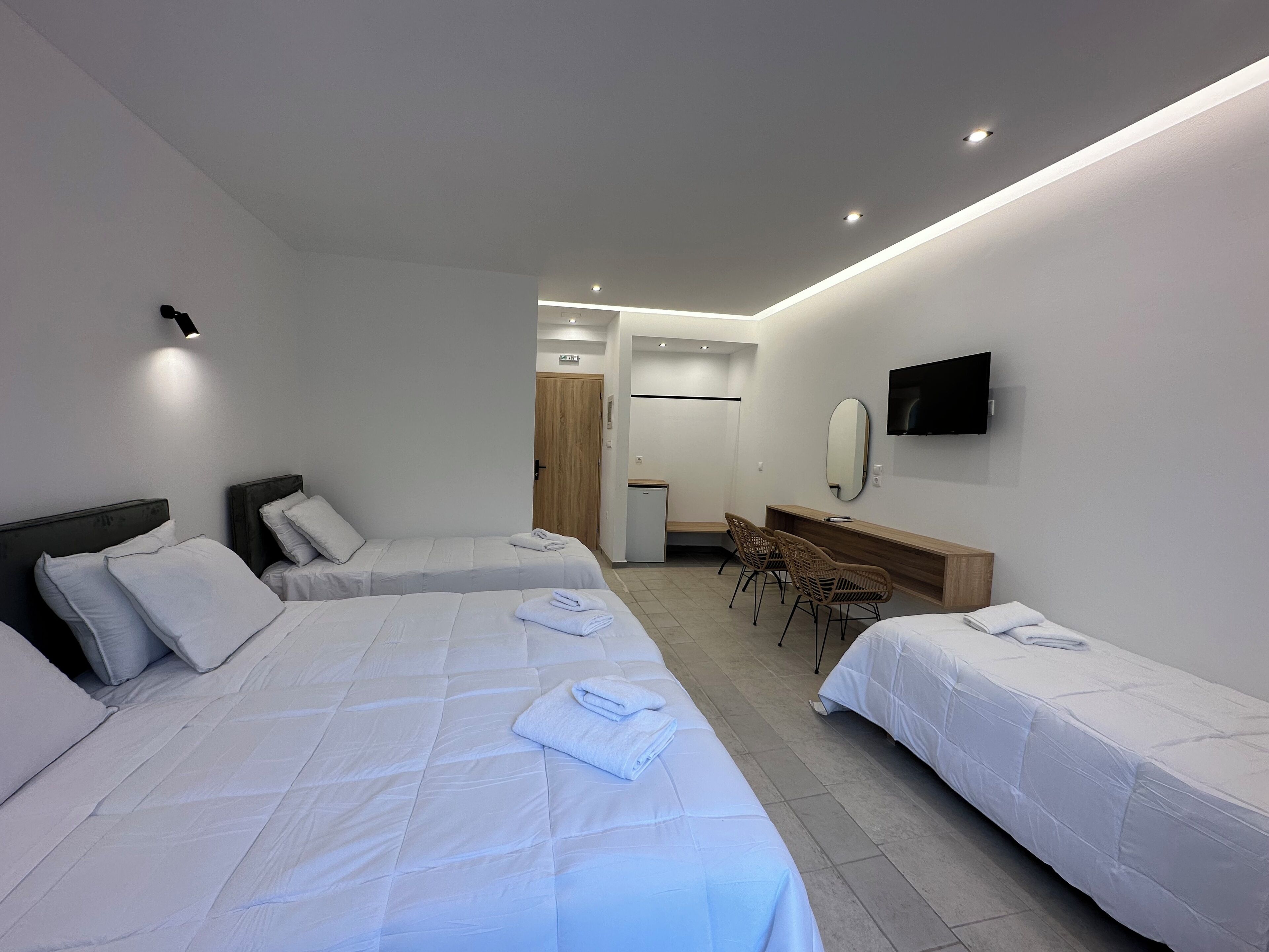 Ett hotellrum med två separata sängar, ett skrivbord, en stol, en TV och en garderob i trä.