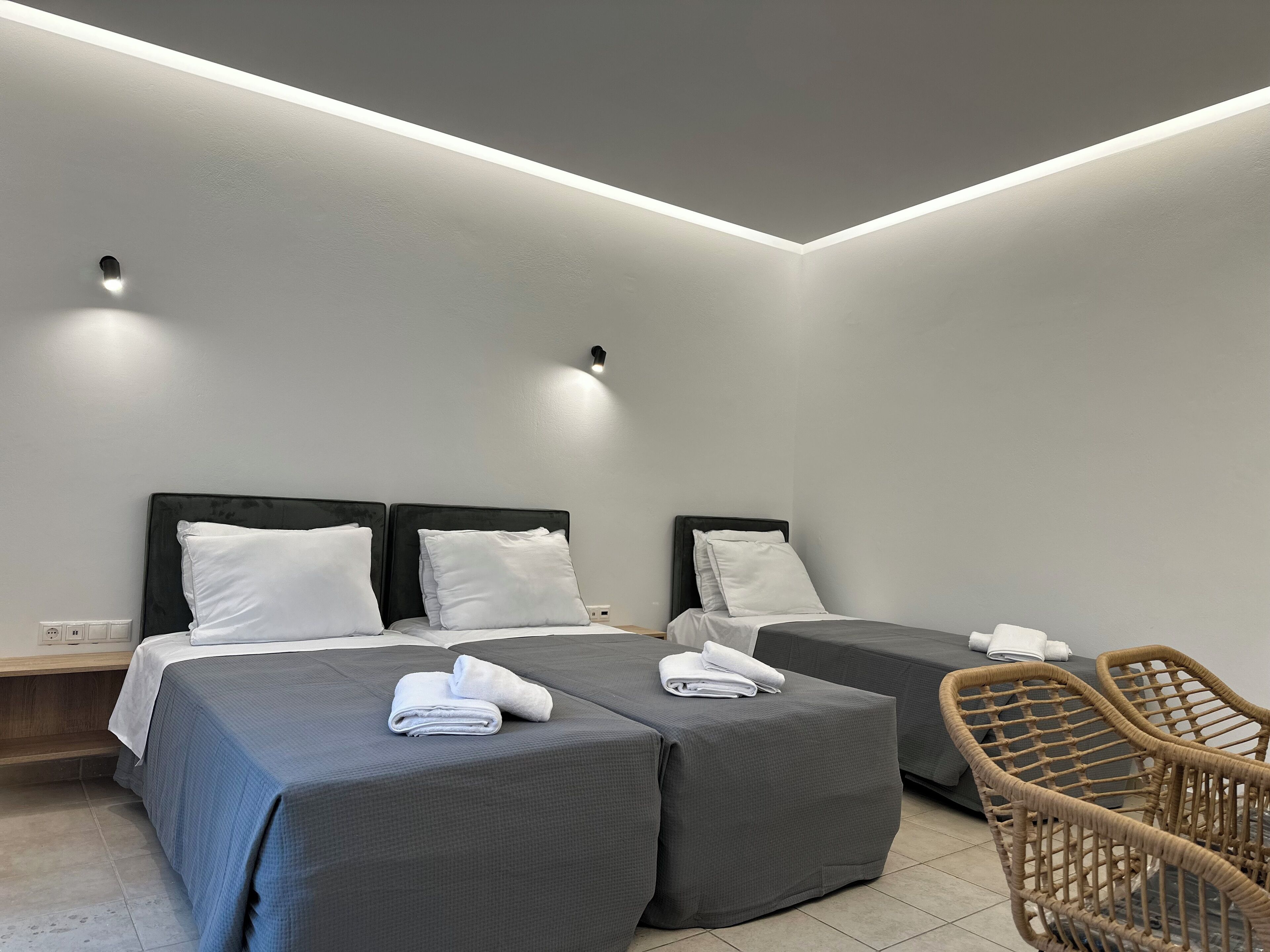 A modern hotel room with two beds, a small seating area, and a ceiling light.