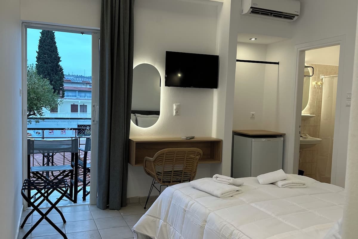 Una habitación de hotel moderna con cama, escritorio con silla, televisor montado en la pared y aire acondicionado.