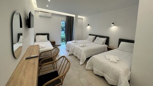 Ein Hotelzimmer mit zwei Betten, einem Holztisch, Korbstühlen und einem großen Spiegel.