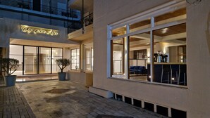 Ein Hotel mit Eingang, einer Neonreklame, großen Fenstern und einer sichtbaren Kaffeemaschine im Inneren.