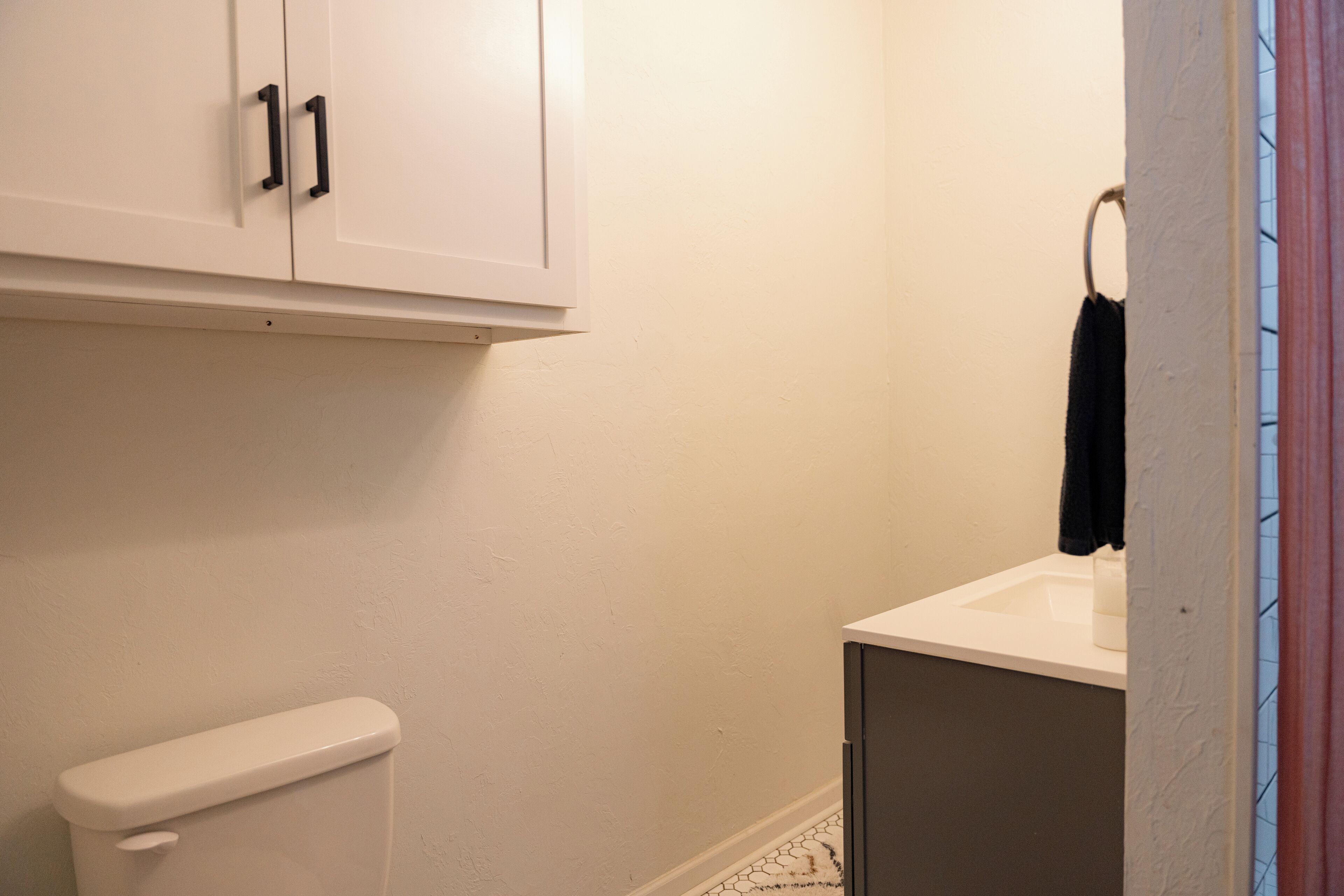 Un baño con inodoro, lavamanos y armarios.