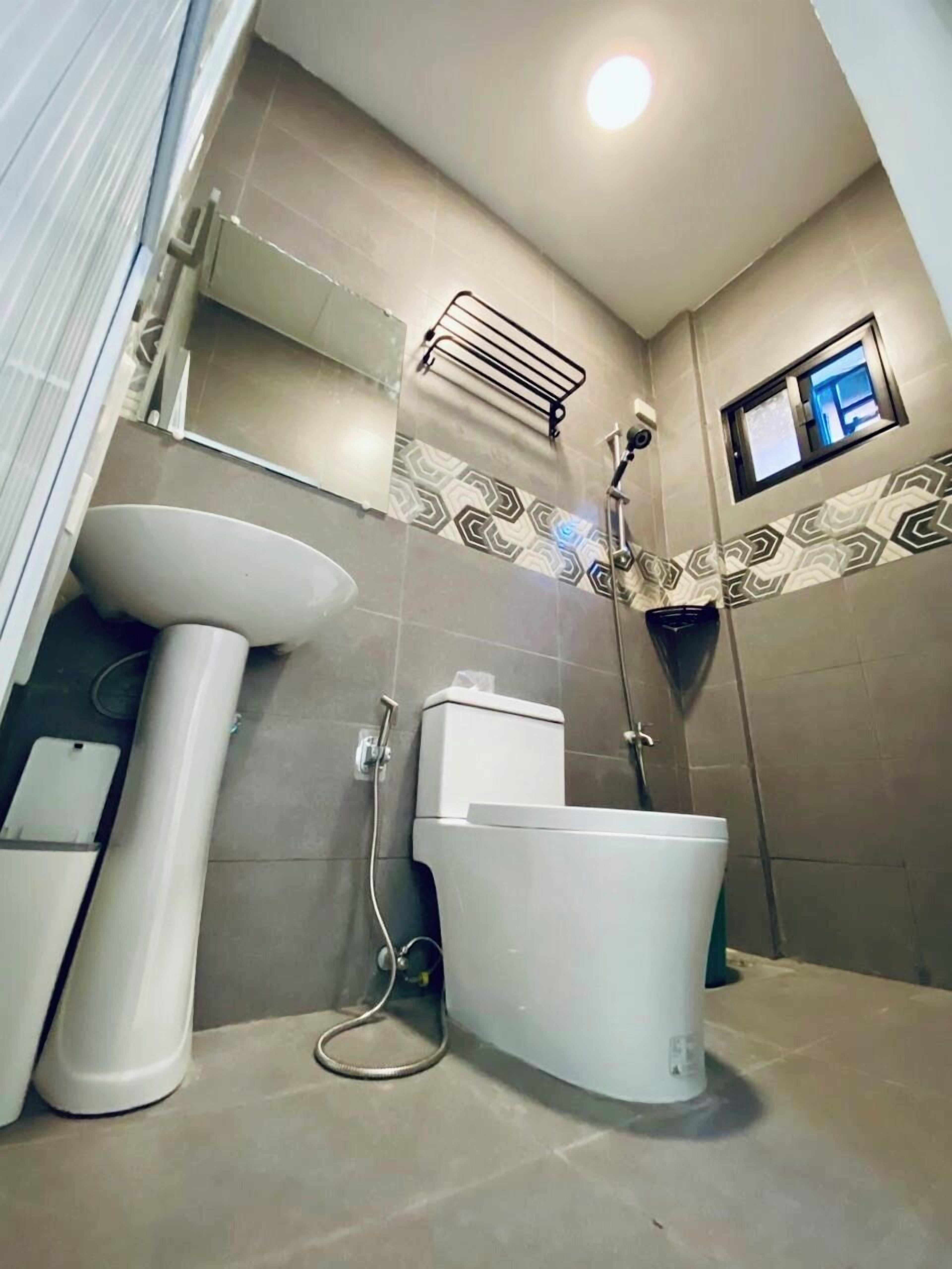 Ein Badezimmer mit Toilette, Bidet und Waschbecken, einer Dusche und einem kleinen Fenster.