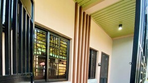 A corridor with a tiled floor, a black gate, a small plant, and a door. - Francheska Suite: Minimalist Comfort Near Cavinti’s Natural Wonders (Cavinti)