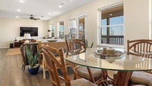 A spacious dining area with a glass-top table surrounded by wooden chairs, a large window with a view, and a ceiling fan. - Hawk's View- Mountain Cottage! (Jasper)