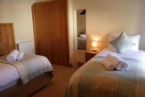 Une chambre d’hôtel avec deux lits, une armoire en bois, une table de chevet avec une lampe et un miroir au mur.