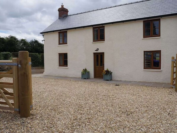 Une maison à deux étages avec une allée en gravier et un portail en bois.