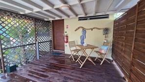 A wooden deck with a table and chairs, a fire extinguisher, and a wooden wall.