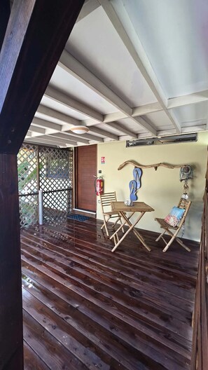 A wooden deck with a table and chairs, a fire extinguisher, and a wooden swing.