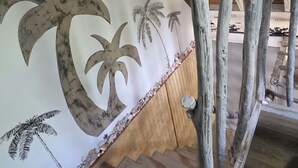 A staircase with wooden beams and a wall with palm tree designs.