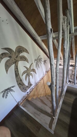 A staircase with wooden beams and a wall with palm tree designs.