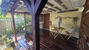 A wooden deck with a table and chairs, surrounded by a wooden fence and potted plants.