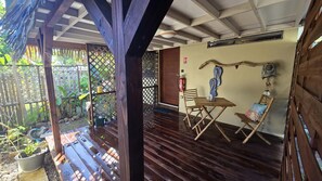 A wooden deck with a table and chairs, surrounded by a wooden fence and potted plants.