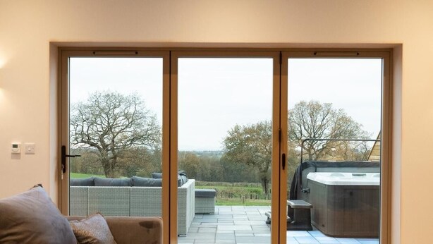 Een moderne woonkamer met een bank, een salontafel en een schuifdeur die leidt naar een terras met een barbecue.