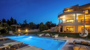 Un edificio moderno a più piani con piscina, area salotto esterna e un balcone ben illuminato.