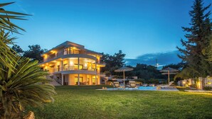 Una casa a più piani con piscina e zona relax all'aperto.