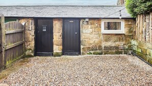 A stone building with two black doors and a small window.