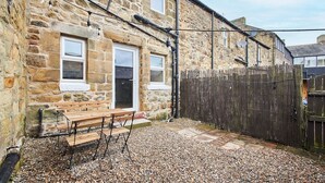 A stone building with a wooden bench and a gravel patio.