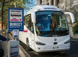 Un autobús blanco con el nombre de la marca 'Terravision' y la palabra 'Direct' estacionado en una calle de la ciudad.