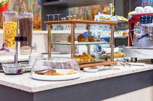 Mostrador de panadería con diversos productos horneados, máquinas de café y tazas.