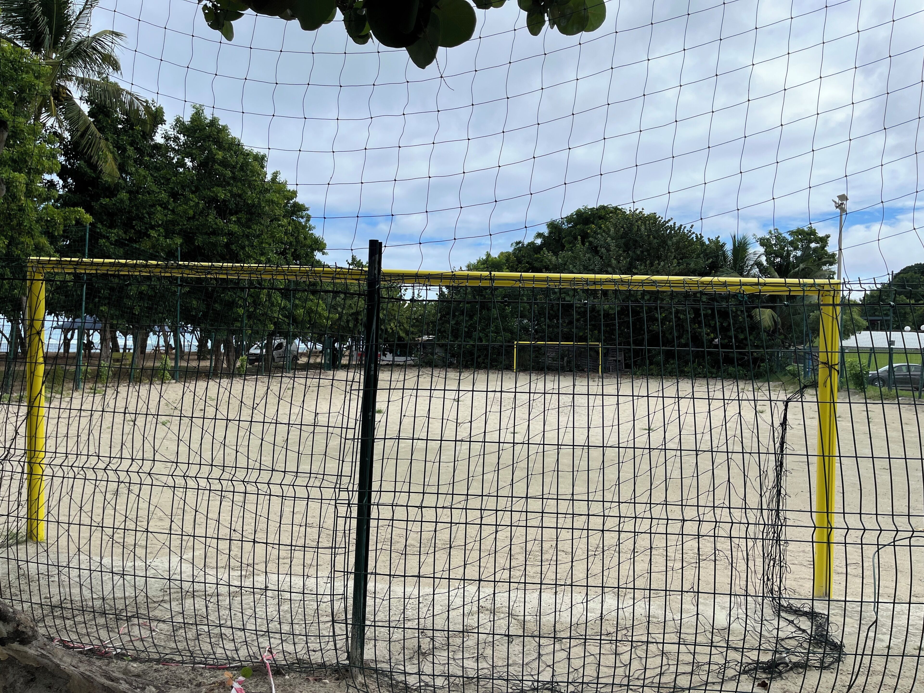 A sandy sports field with a netted goalpost.