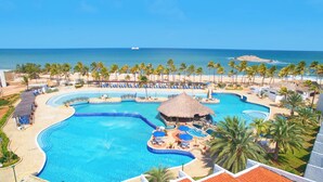 Un complexe hôtelier doté d’une grande piscine, d’une plage et de palmiers.