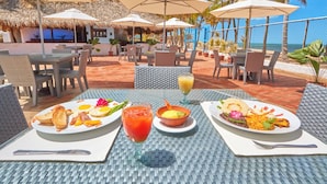 Une table à manger avec des assiettes remplies de nourriture, une boisson et un verre de jus de fruits.