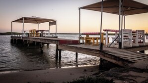 A pier with covered seating areas and tables extending into a body of water. - The Fisherman's Porch (Bergrivier)