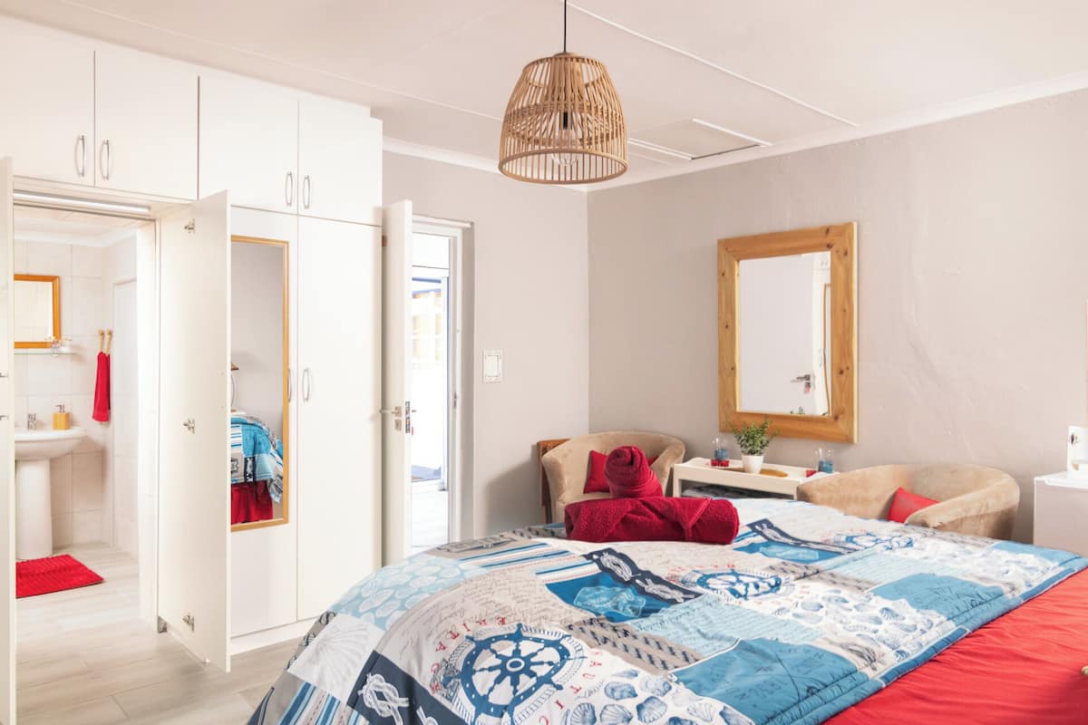 A bedroom with a bed, a bedside table, a mirror, and a wardrobe.