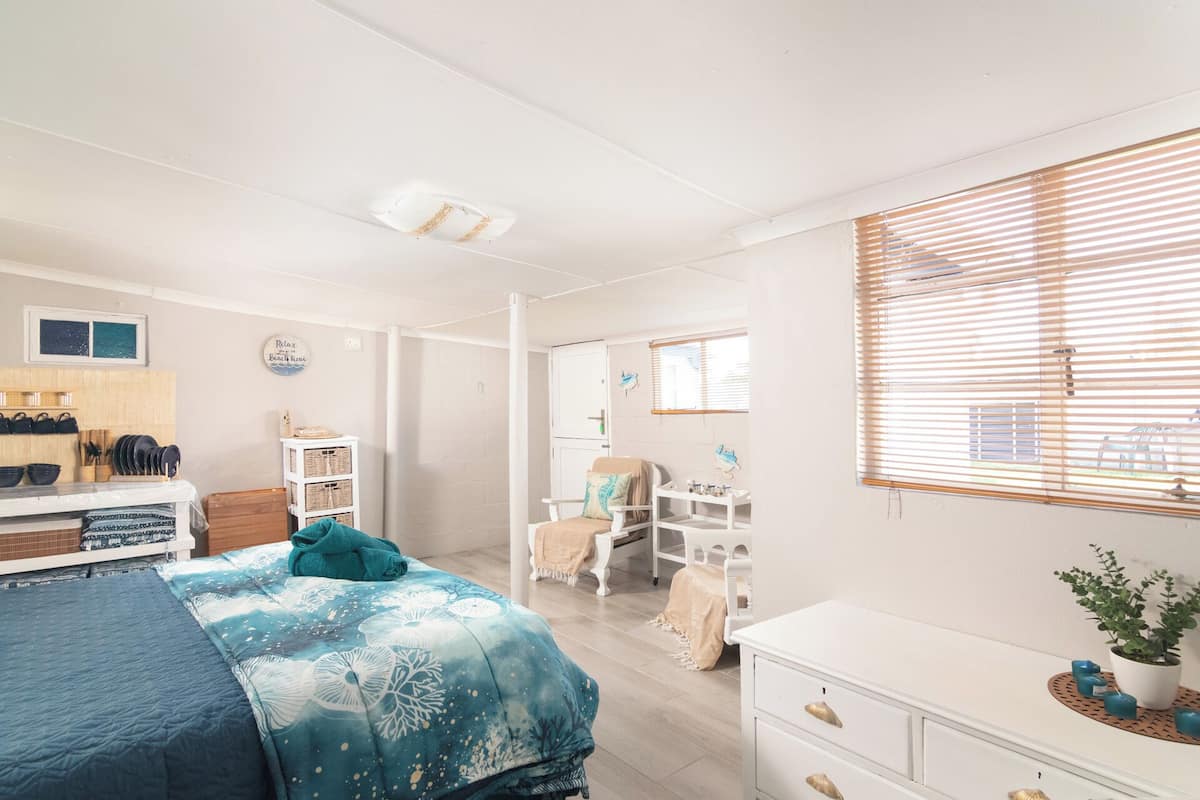A bedroom with a bed, a dresser, a vanity, and a shower area.