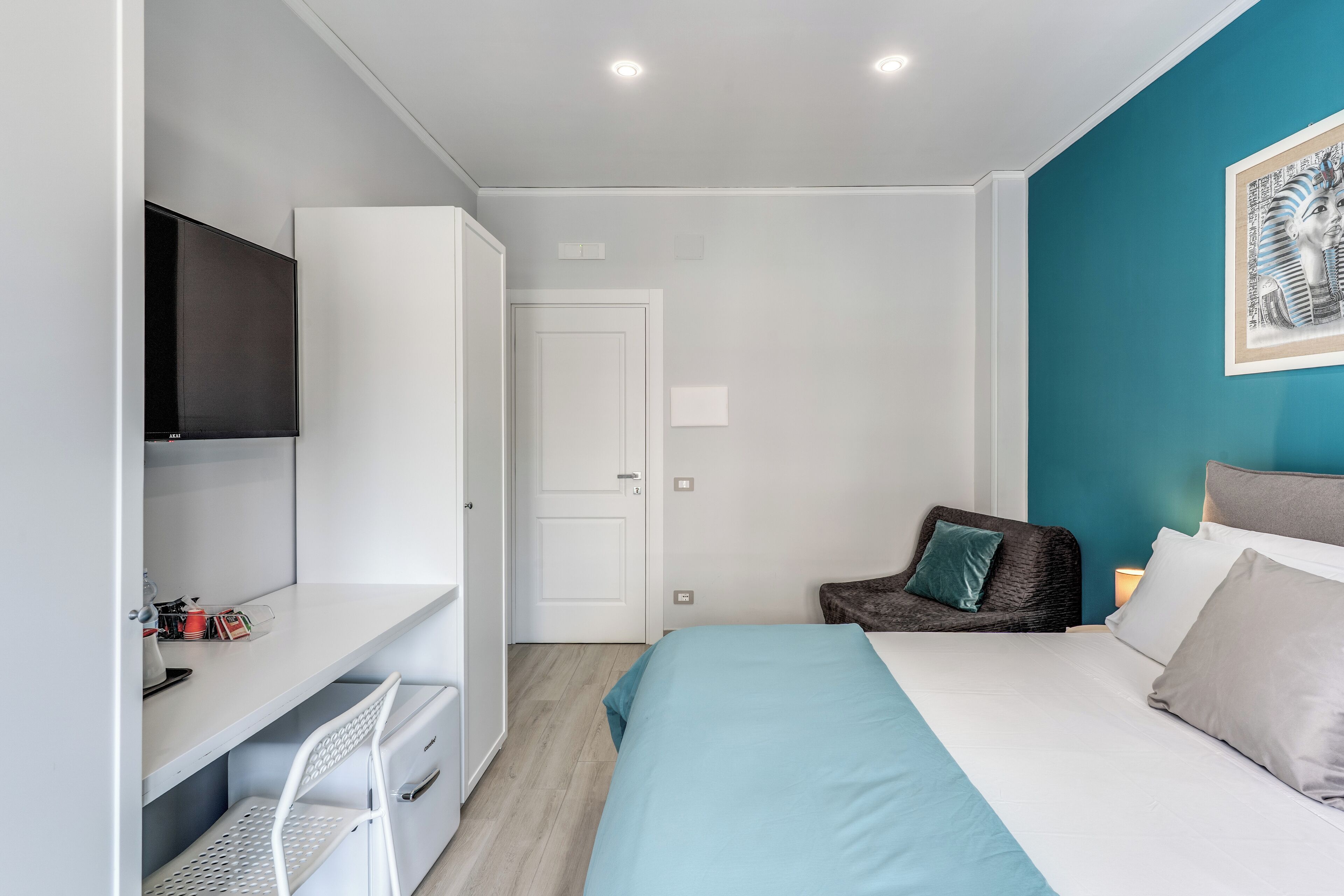 Une chambre à coucher moderne avec un lit, un bureau, une chaise et un téléviseur.