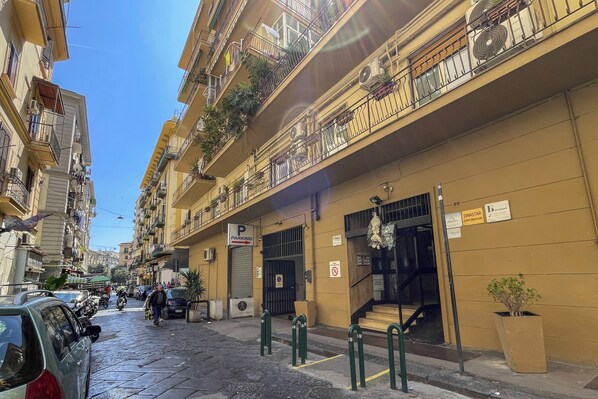 A multi-story building with balconies, a parking sign, and a staircase leading to an entrance. - Marmolo Room (Naples)