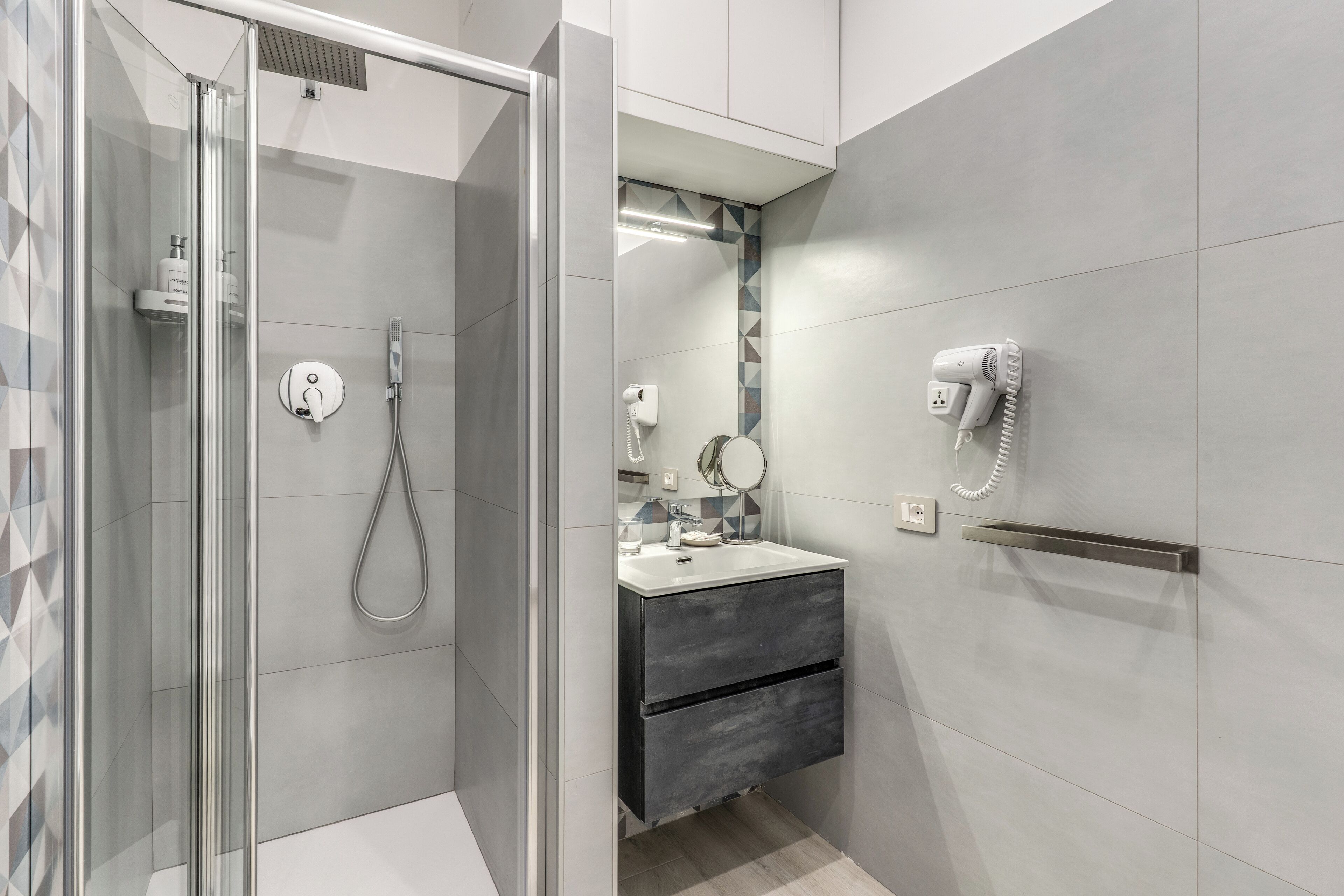 A modern bathroom with a glass-enclosed shower, a vanity with a mirror, and a towel rack.