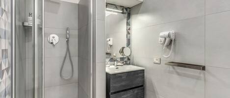 A modern bathroom with a glass-enclosed shower, a vanity with a mirror, and a towel rack.