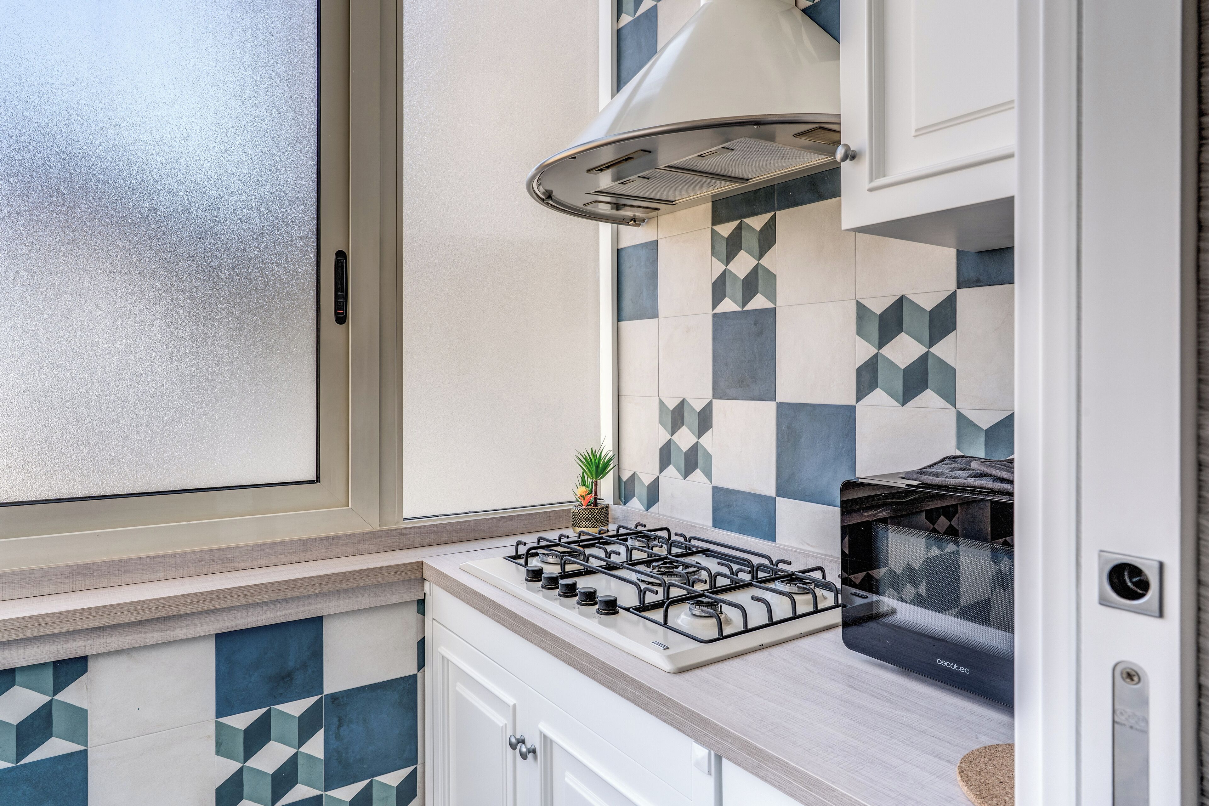 A kitchen with a gas stove, a built-in oven, and a window with frosted glass.
