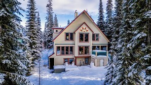 A multi-story house surrounded by snow-covered trees. - Pet friendly chalet right on the ski way, steps from tube town pet friendly too! (Silver Star Mountain)