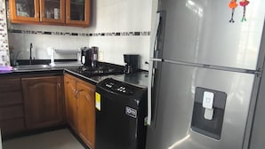 A kitchen with wooden cabinets, a stainless steel refrigerator, a stove, and a coffee maker. - Castle house (Cartagena)