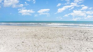 A wide sandy beach with gentle waves and a clear blue sky. - Bluewater Resort V408A (Myrtle Beach)