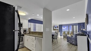 A modern kitchen with white cabinets, a black refrigerator, and a granite countertop. - Bluewater Resort V408A (Myrtle Beach)