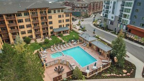 A hotel with a pool area, outdoor seating, and a view of mountains.