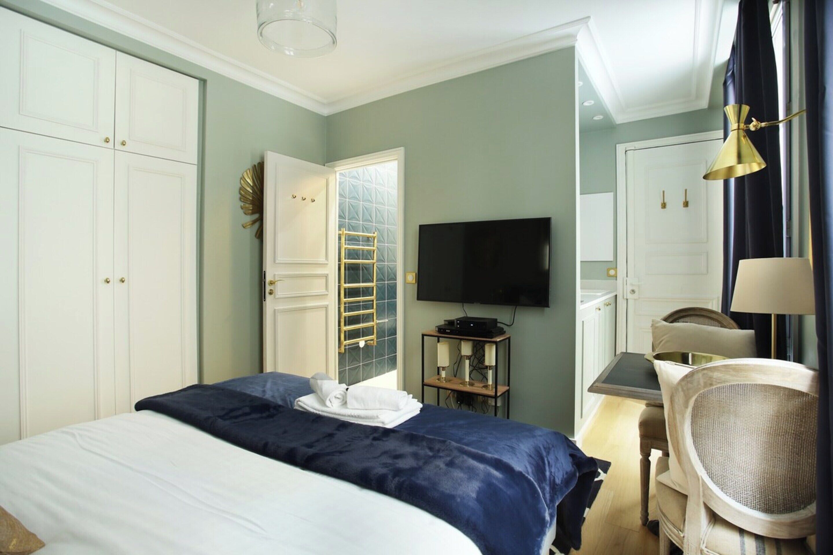 Une chambre d’hôtel équipée d’un lit, d’un bureau, d’une chaise, d’une télévision et d’une armoire.